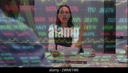 Image des données financières et des graphiques sur la femme biraciale au bureau Banque D'Images