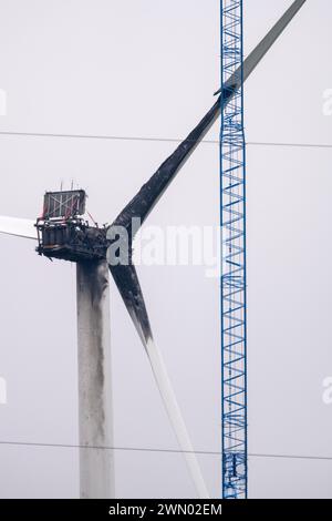 Greifswald, Allemagne. 28 février 2024. Une grue est installée sur une éolienne pour démonter l’éolienne près de Greifswald qui a été détruite par un incendie. Mardi (23.01.2023), une éolienne près de Greifswald a pris feu. Les pompiers ont dû laisser brûler la nacelle de manière contrôlée. Selon la police, des défauts techniques en étaient la cause. Crédit : Stefan Sauer/dpa/Alamy Live News Banque D'Images