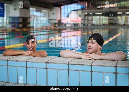 Portrait de deux jeunes femmes et hommes athlète nageurs en piscine avec des lunettes Banque D'Images