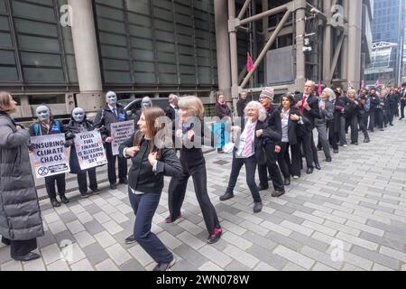 Londres, Royaume-Uni. 28 février 2024. Les danseurs de robe de ville devant Lloyds. Les manifestants de la rébellion d'extinction ont défilé de Trinity Square à un festival devant le bâtiment d'assurance de Lloyds, certains en tenue professionnelle. Ils exigent que le secteur de l'assurance refuse de fournir une couverture pour les développements des combustibles fossiles, car ceux-ci menacent notre avenir. 40% de la production mondiale de combustibles fossiles est assurée par Lloyds. La manifestation pacifique comprenait de la musique, des discours et des danses. Peter Marshall/Alamy Live News Banque D'Images