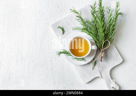 Tasse en verre de thé de romarin sain avec bouquet de romarin frais sur fond rustique, concept de boisson chaude à base de plantes d'hiver, salvia rosmarinus Banque D'Images