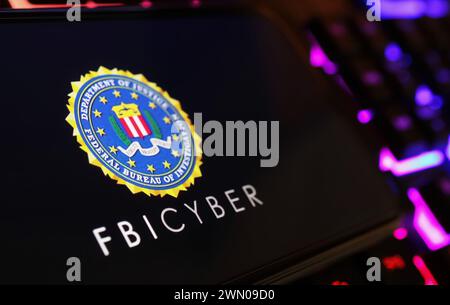 Viersen, Allemagne - 9 janvier. 2024 : écran de smartphone avec lettrage logo de FBI Cyber sur le clavier de l'ordinateur Banque D'Images