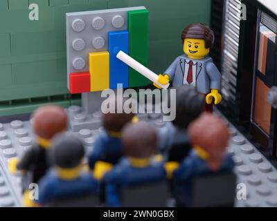 Tambov, Fédération de Russie - 28 février 2024 Lego hommes d'affaires minifigures ayant une réunion dans une salle de réunion et discutant des graphiques montrant la re Banque D'Images