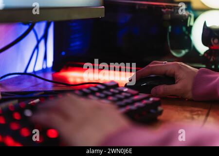 Mains d'un joueur jouant à des jeux vidéo avec son clavier LED et sa souris dans sa configuration de jeu Banque D'Images