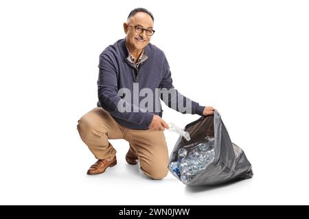 Homme mature collectant des bouteilles en plastique dans un sac à déchets isolé sur fond blanc Banque D'Images