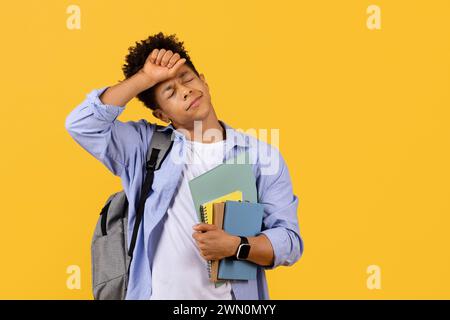 Étudiant noir stressé avec des livres, submergé par la charge d'étude Banque D'Images