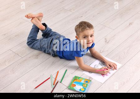 Mignon petit garçon dessinant sur le sol chaud à la maison. Système de chauffage Banque D'Images