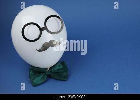 Visage de l'homme fait de ballon, fausse moustache, lunettes en papier et noeud papillon sur fond bleu. Espace pour le texte Banque D'Images