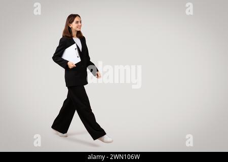 Une femme professionnelle confiante avance avec une planche à pince à la main Banque D'Images