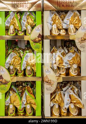 Alba, Italie - 27 février 2024 : Ferrero Rocher oeufs de Pâques chocolat affiché sur des présentoirs colorés, de marque de cartons en carton à vendre en Italie Banque D'Images