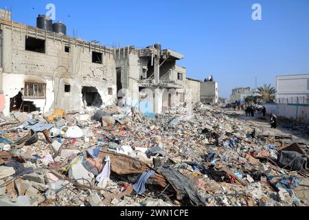 Gaza. 28 février 2024. Les gens passent devant des bâtiments détruits dans la ville de Khan Younis, dans le sud de la bande de Gaza, le 28 février 2024. Le nombre de morts palestiniens dans la bande de Gaza est passé à 29 954 alors que l'armée israélienne en a tué 76 au cours des dernières 24 heures, a déclaré mercredi le ministère de la santé dirigé par le Hamas. Crédit : Rizek Abdeljawad/Xinhua/Alamy Live News Banque D'Images