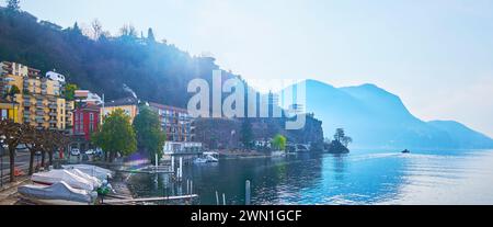 La vue du matin depuis la rive du lac de Lugano, observant le petit port avec des bateaux et des Alpes brumeuses, Lugano, Tessin, Suisse Banque D'Images