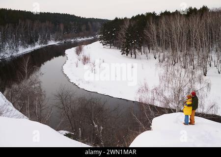 Extrême long plan de couple méconnaissable debout sur la falaise un jour froid d'hiver profitant de paysages magnifiques Banque D'Images