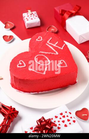 Gâteau bento en forme de coeur avec boîtes cadeaux et bougies sur fond de couleur. Célébration de la Saint-Valentin Banque D'Images