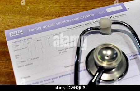 Photo du dossier datée du 10/09/14 d'un formulaire d'inscription aux services de médecin de famille du NHS et d'un stéthoscope. Une politique qui pourrait signifier que les gens doivent voyager s'ils veulent voir un médecin généraliste pour un rendez-vous le jour même a suscité des inquiétudes au sujet de la sécurité des patients et de la continuité des soins dans un quartier de Londres. Date d'émission : jeudi 29 février 2024. Banque D'Images