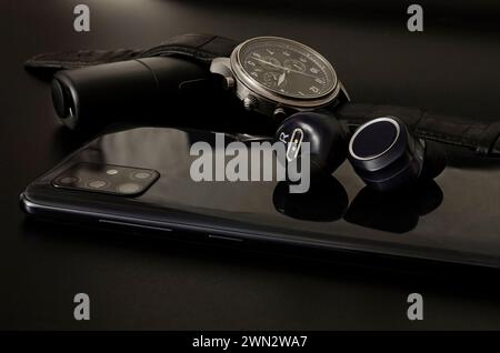 Gadgets sur fond sombre : une montre, un casque, un chauffe-tabac et un téléphone. Banque D'Images