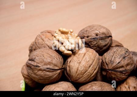 Noix craquelée présentant des graines comestibles parmi des graines entières, cette image présente une vue rapprochée de noix entières et craquées sur une surface en bois. Banque D'Images