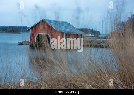 Un bateau en bois rouge se jette au bord de la mer dans l'archipel finlandais, par temps poussiéreux. Banque D'Images