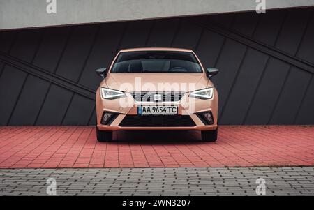 SIÈGE beige Ibiza en face du bâtiment moderne. Vue de face de la berline espagnole compacte ivoire pâle dans un cadre urbain. La voiture est garée sur des carreaux rouges. Banque D'Images