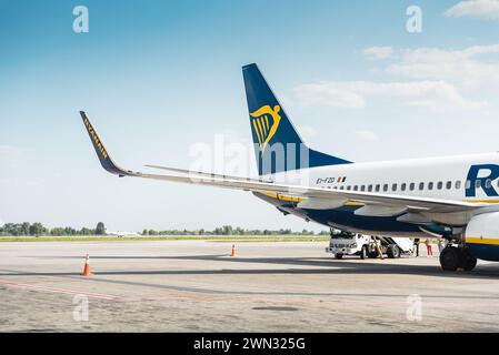 Ryanair Boeing 737 (EI-FZD) par une journée ensoleillée. Embarquement d'un avion sur l'aire de trafic ; jet régional roulant le long de la voie de circulation en arrière-plan Banque D'Images