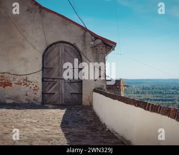 Vieille porte en bois au dernier étage du château de Palanok par une journée ensoleillée. Terrasse de haut château surplombant le paysage vallonné de transcarpathie Banque D'Images