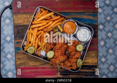 photographie de portrait d'un plateau rempli de poulet frit et de frites à la mayonnaise et à la moutarde, tourné en grand angle Banque D'Images