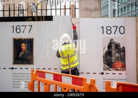 Un entrepreneur complète une palissade protectrice qui montre le visage de Samuel Pepys et les dates historiques du 12ème siècle L'église All Hallows est entourée par l'activité de construction moderne dans la ville de Londres, le quartier financier de la capitale, le 28 février 2024, à Londres, en Angleterre. Toutes les taches de reliefs (qui signifie construit à partir de pierre, pas de bois) ont survécu au Grand incendie de Londres en 1666 et malgré de lourds dommages, au Blitz de la seconde Guerre mondiale. Le site situé au 50 Fenchurch comprend actuellement la coloration de la tour de tous les reliefs classée Grade I et la crypte de la chapelle Lambe classée Grade II, mais la construction i. Banque D'Images