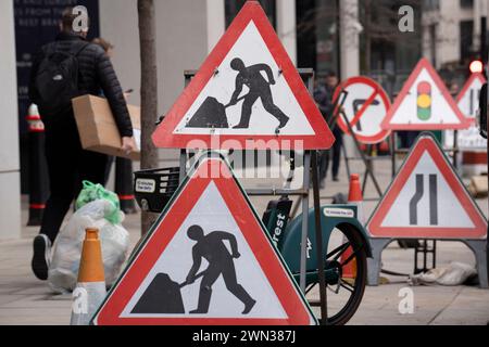 Des panneaux d'avertissement homme au travail pendant les travaux de rue effectués par des entrepreneurs dans la City de Londres, le quartier financier de la capitale, le 28 février 2024, à Londres, en Angleterre. Banque D'Images