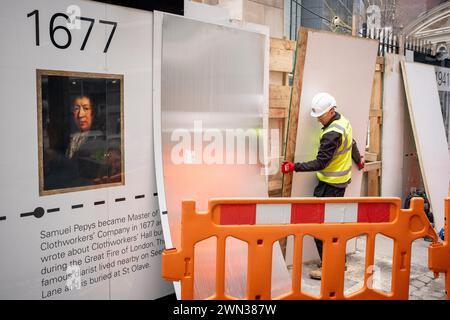 Un entrepreneur complète une palissade protectrice qui montre le visage de Samuel Pepys et les dates historiques du 12ème siècle L'église All Hallows est entourée par l'activité de construction moderne dans la ville de Londres, le quartier financier de la capitale, le 28 février 2024, à Londres, en Angleterre. Toutes les taches de reliefs (qui signifie construit à partir de pierre, pas de bois) ont survécu au Grand incendie de Londres en 1666 et malgré de lourds dommages, au Blitz de la seconde Guerre mondiale. Le site situé au 50 Fenchurch comprend actuellement la coloration de la tour de tous les reliefs classée Grade I et la crypte de la chapelle Lambe classée Grade II, mais la construction i. Banque D'Images