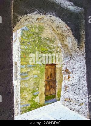 Le mur de pierre, recouvert de mousse verte et la porte en bois minable à travers la petite fenêtre cintrée, Bre, Tessin, Suisse Banque D'Images