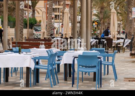 Plage de San Juan, Alicante, Espagne, 02-26-2024.tables préparées pour manger sur la terrasse des restaurants le long de la promenade sur la plage de San Juan de A. Banque D'Images