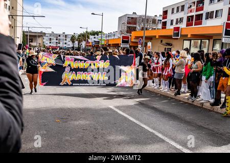 Un homme tenant une pancarte mène un défilé dans une rue animée, avec une grande foule regardant Banque D'Images