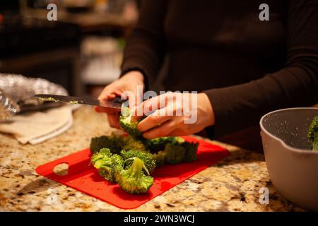 Une femme en chemise noire cuisinant avec des ustensiles sur une table Banque D'Images