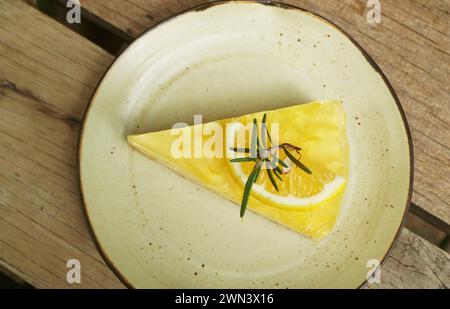 Tranche de délicieuse tarte au fromage à la crème sucrée et acidulée au citron sur une table en bois Banque D'Images