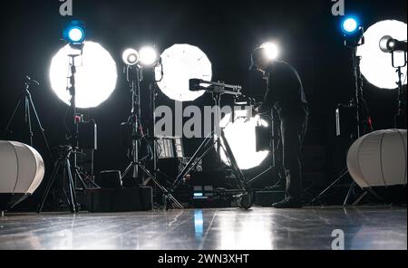 Un homme assemblant la vidéo LED moderne puissante et l'éclairage photo dans Dark production Studio Banque D'Images