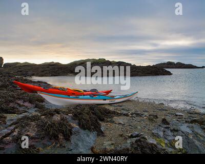 Anglesey, Royaume-Uni - 11 janvier 2024 : deux kayaks de mer sur une plage déserte sur l'île d'Anglesey dans le nord du pays de Galles, Royaume-Uni. Pris par une journée calme et nuageuse en hiver. Banque D'Images
