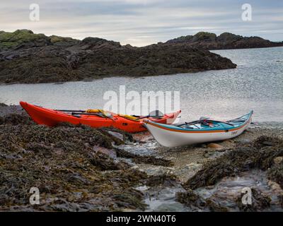 Anglesey, Royaume-Uni - 11 janvier 2024 : deux kayaks de mer sur une plage déserte sur l'île d'Anglesey dans le nord du pays de Galles, Royaume-Uni. Pris par une journée calme et nuageuse en hiver. Banque D'Images