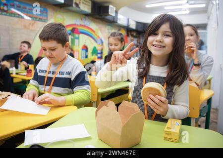 Kharkiv, Ukraine. 19 décembre 2023. Un enfant pose avec son sandwich dans la salle de classe pendant la pause déjeuner. Les enfants ukrainiens suivent des cours dans une école d'une station de métro à Kharkiv, en Ukraine, au milieu de l'invasion russe. De nombreux enfants de Kharkiv ne vont pas à l'école car leurs parents craignent pour leur sécurité en raison de la proximité de la ville avec la frontière russe. Les autorités municipales ont organisé le processus d'éducation pour les enfants dans les classes d'écoles souterraines dans le métro de la ville. (Photo de Mykhaylo Palinchak/SOPA images/Sipa USA) crédit : Sipa USA/Alamy Live News Banque D'Images