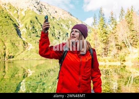 Perdu trekker voyageur des années 30 femme cherchant l'emplacement avec un téléphone intelligent seul dans une forêt près de Morskie Oko. Randonneur femelle a perdu le signal cellulaire et Banque D'Images