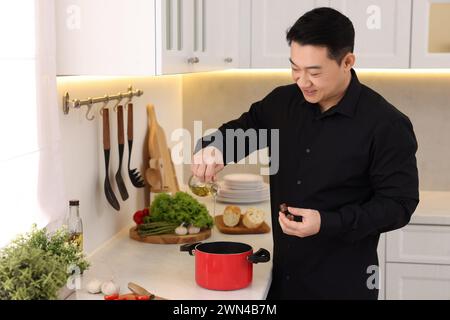 Procédé de cuisson. Homme versant de l'huile dans le pot au comptoir dans la cuisine Banque D'Images