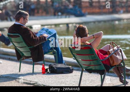 Personnes assises au bord de l'étang du Grand bassin rond dans le jardin des Tuileries un jour d'été à Paris, France. Banque D'Images