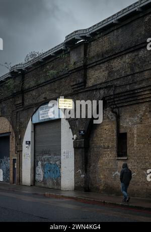 Southwark, Londres, Royaume-Uni : Bermondsey Scrap Metals sous le pont de Londres au viaduc ferroviaire de Greenwich avec une personne passant devant sur Druid Street. Banque D'Images