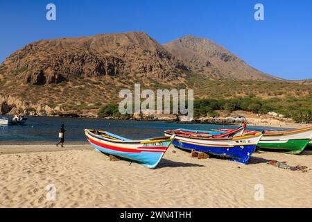 Belle plage de sable blanc avec des bateaux de pêche en bois coloré et baie calme et montagne rocheuse à Tarrafel Santiago île cabo verde Banque D'Images