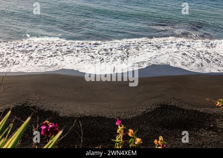 Regardant vers le bas une figure solitaire debout au bord de la mer tandis que de douces vagues se brisent sur la plage volcanique noire praia de fonte bila sao filipe fogo Island CV Banque D'Images