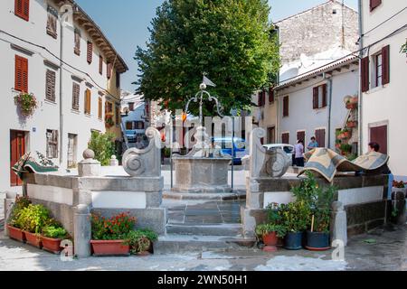 Un touriste regarde une fontaine historique dans la ville de Buzet. L'architecture historique est utilisée comme un endroit pour sécher les tapis. Buzet. Istrie, Croatie, 2011 Banque D'Images