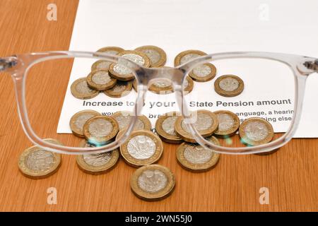 Lettre sur une augmentation de la pension d'État vue à travers un pari de verres, avec des pièces britanniques d'une livre Banque D'Images
