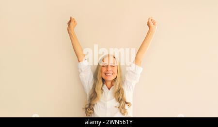 Heureuse femme chanceuse gestionnaire d'employé dans la chemise de bureau s'amusant ou sent la victoire levant ses mains au travail Banque D'Images