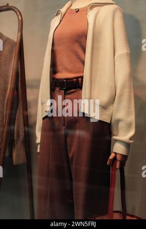 Détails de mode d'un pull tricoté blanc et d'un pantalon marron avec une ceinture en cuir. Vêtements et accessoires de mode décontractés pour femmes Banque D'Images