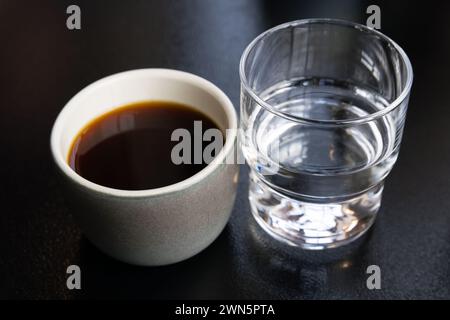 Tasse de café filtre et verre d'eau se tiennent sur la table noire, photo en gros plan avec mise au point sélective Banque D'Images