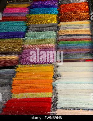 brins de colliers en verre coloré très brillant dans de nombreuses couleurs vibrantes à vendre dans la boutique spécialisée dans les créations de bijoux personnalisés Banque D'Images